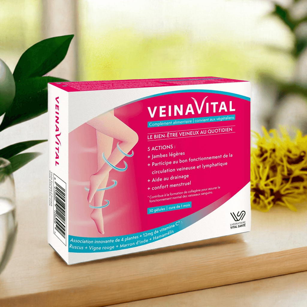 Boîte de Veinavital posée sur une table en bois, entourée de plantes et de fleurs, dans un décor lumineux – complément naturel pour la circulation sanguine et le confort veineux.